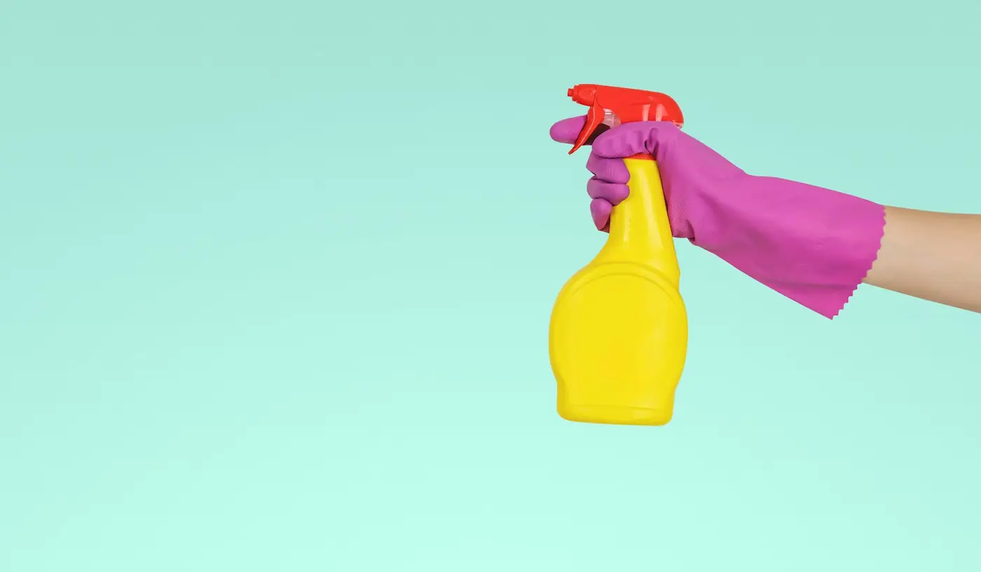 Städspray och handske mot mintgrön bakgrund